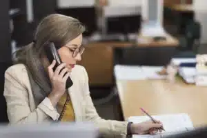 ffice employee taking phone order while writing on notepad - a payment security risk