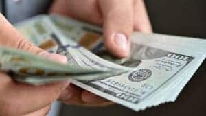 Hand holding cash to pay merhcant payment processing fees