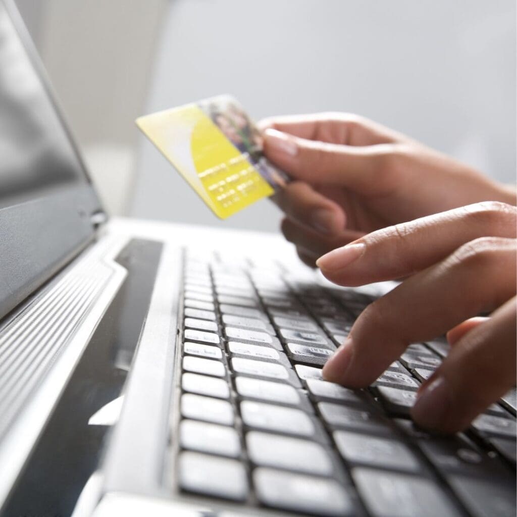 Person holding credit card near their computer