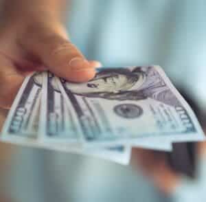 Hand holding hundred dollar bills - merchant payment being held