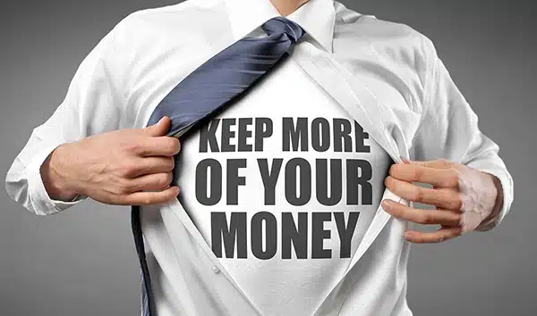 A businessman in a white dress shirt and blue tie pulling his shirt open to reveal a t-shirt underneath that reads "KEEP MORE OF YOUR MONEY" in bold black letters.