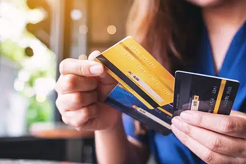 Close-up of a woman holding several premium and business credit cards, representing the complex card mix that small business owners must manage to avoid interchange downgrades