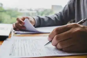 Navigating the 2026 digital shift master the irs cp53e and electronic mandates intellipay Close-up of a person's hands diligently filling out a 2017 U.S. Individual Income Tax Return form with a pen, emphasizing the traditional paper filing process now being phased out by new 2026 electronic mandates.
