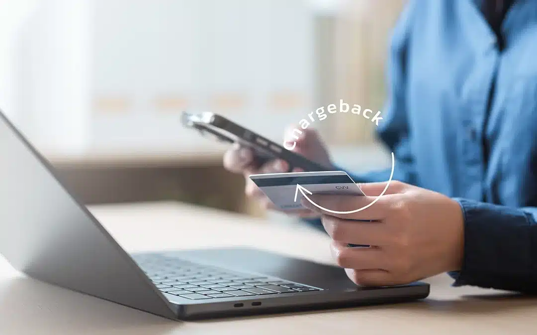 Person holding a credit card and smartphone in front of a laptop with the word “chargeback” highlighted, illustrating online payment disputes for small businesses