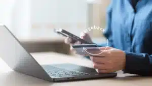 Person holding a credit card and smartphone in front of a laptop with the word “chargeback” highlighted, illustrating online payment disputes for small businesses