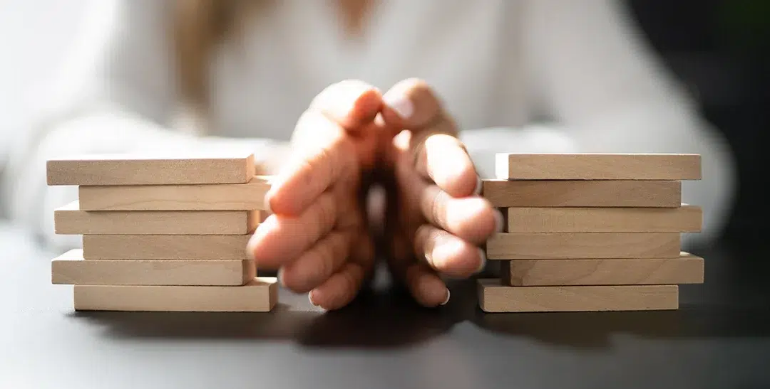 Hands carefully stacking wooden blocks representing structured dispute resolution and payment compliance for utility billers