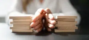 Hands carefully stacking wooden blocks representing structured dispute resolution and payment compliance for utility billers